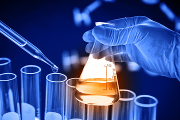 Wall Mural - flask in scientist hand with lab glassware background
