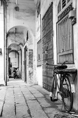 Monochrome photo of retro bicycle in a narrow alley, old town