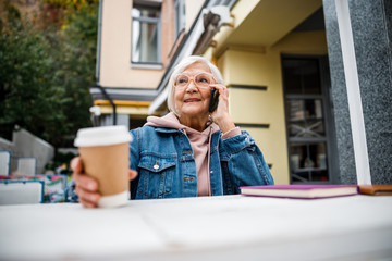 Poster - Happy mature woman making call in cafe stock photo