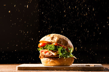 home made hamburger made by white sesame bun, tomato slice, salad, cheese, grilled meat and onion on