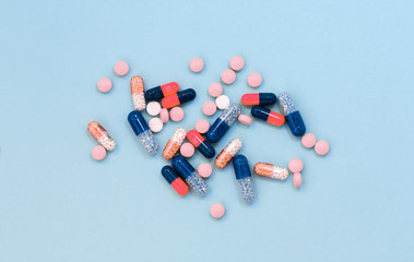 Heap of colorful pills, tablets, capsules on blue background. Drug prescription for treatment medication health care concept wth copy space.