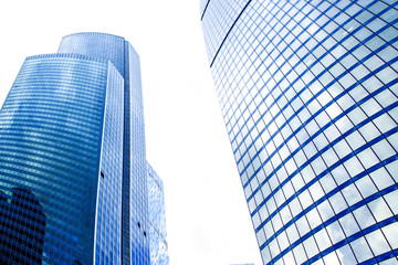 Low angle view of tops of modern new business corporate buildings against the blue sky.