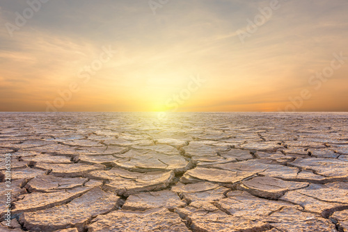 Fotomural Landscape of soil drought cracked on sky sunset background