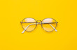 © Touchr - Eye glasses isolated on yellow background.