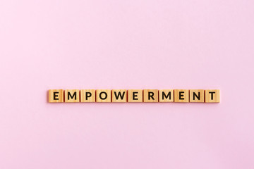 Wall Mural - Empowerment text wood blocks. Pink background.