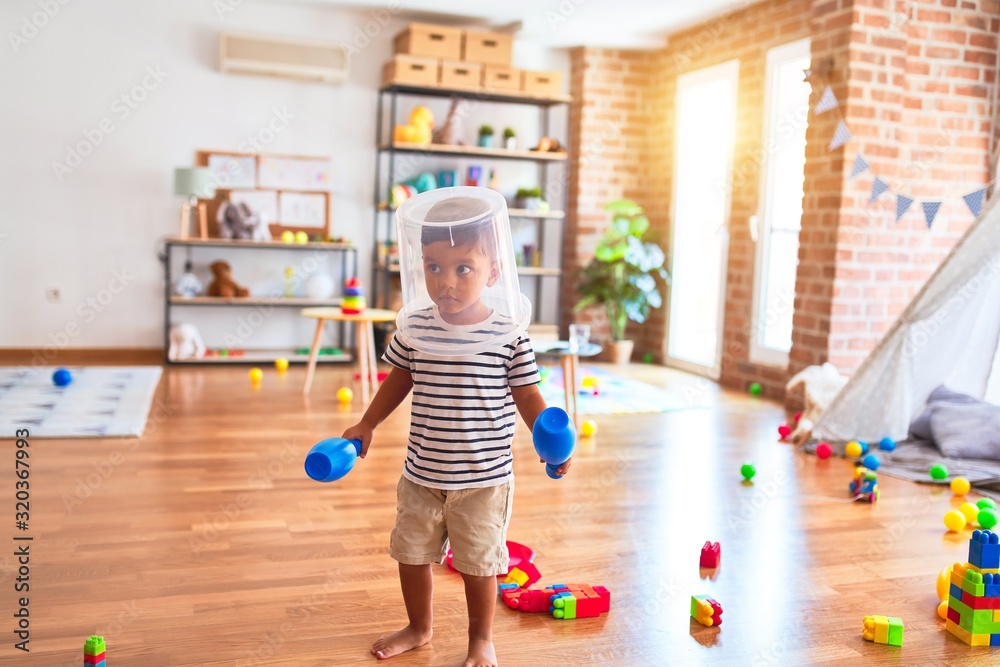 Beautiful toddler boy playing with plastic basket at kindergarten - obrazy, fototapety, plakaty 