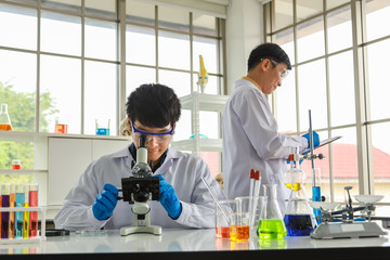 Portrait of two asian professional senior and young doctor scientist working and using microscope and research in working laboratory.