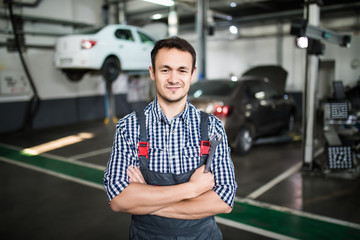 Wall Mural - Portrait of a young beautiful car mechanic in a car workshop, in the background of service.