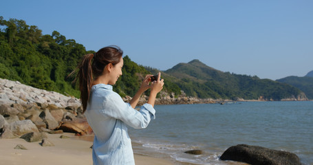 Canvas Print - Woman take photo on cellphone with the sea