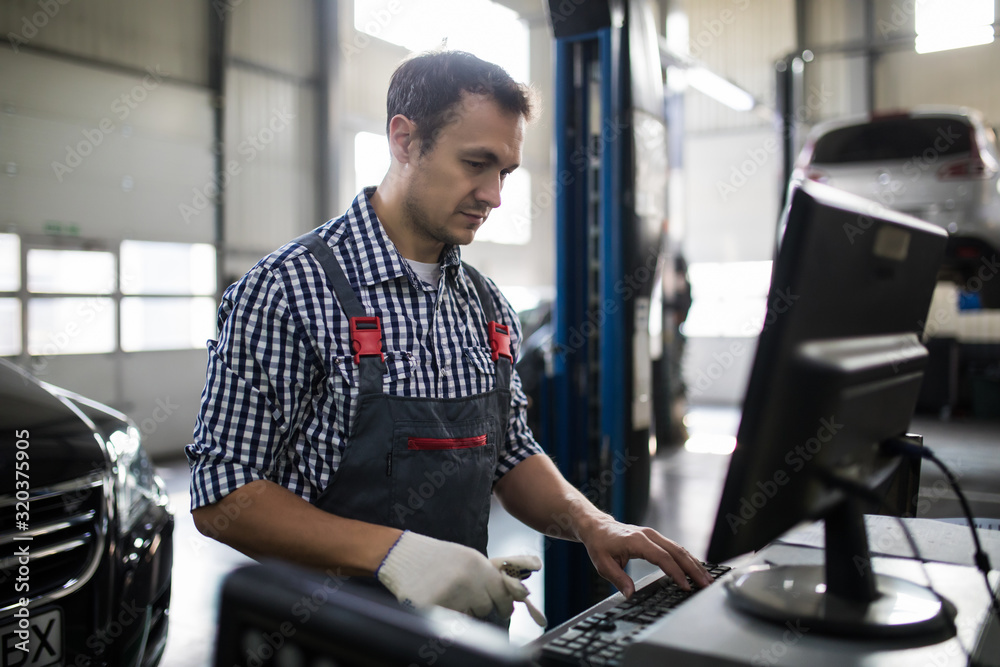 Portrait of happy male mechanic touching computer monitor in auto ...