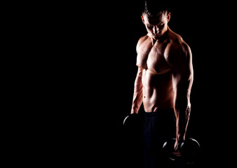 Wall Mural - Strong, fit and sporty bodybuilder man over black background.