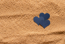 Three Blue Hearts Lie On The Surface Of The Sand.