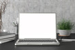 © dimamoroz - Workspace with blank laptop monitor white screen mock up on the dark desk near concrete wall. 3d illustration