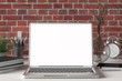 © dimamoroz - Workspace with blank laptop monitor white screen mock up on the white desk near red brick wall. 3d illustration