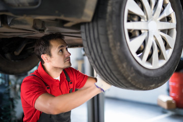 Wall Mural - Young man mechanic changing a car wheel.