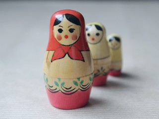 Wooden Russian matryoshka dolls in folk style, girls with painted dresses and veiled heads covered with babushka shawl.