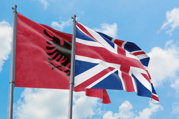 United Kingdom and Albania flags waving in the wind against white cloudy blue sky together. Diplomacy concept, international relations.