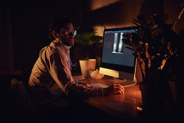 Wall Mural - Smart medic in glasses is working with x-ray screens using a computer at dark office.