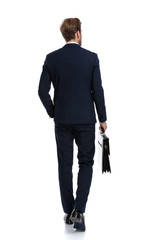 Wall Mural - sexy young businessman in navy blue suit holding suitcase