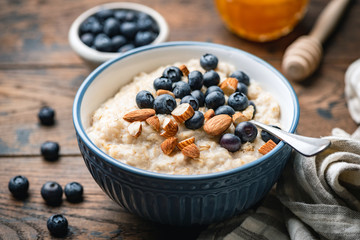 oatmeal porridge with blueberries, almonds in bowl on wooden table background. healthy breakfast foo