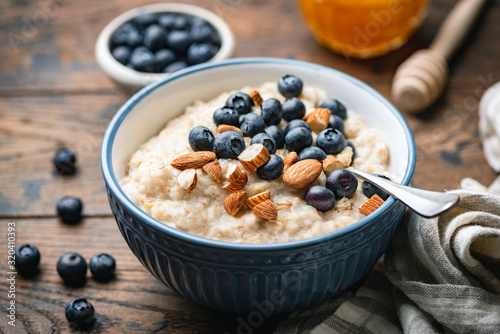 Cuadros en Lienzo Oatmeal porridge with blueberries, almonds in bowl on wooden table background