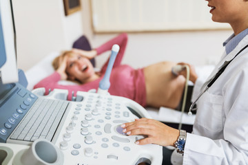 Wall Mural - Obstetrician examining pregnant belly by ultrasonic scan.