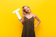 young blonde woman excited, happy, joyful, holding the letter T of the alphabet to form a word or a sentence.