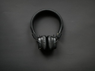 Modern black headphones on colored background