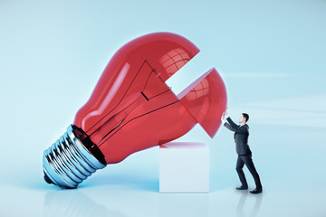 Wall Mural - Businessman pushes a big red light bulb.