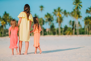 adorable little girls and young mother on white beach