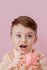 Wall Mural - Happy little boy with a gift . Photo isolated on pink background. Smiling boy holds present box. Concept of holidays and birthday