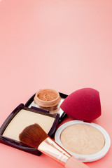 Set of colorful cosmetics on pink wooden table background, base for make-up in the form of a cushion. Copy space