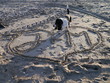 Serce narysowane na piasku przez zakochanych. Na sercu napis J+M, stoi w nim pies rasy basset hound. Wyznanie miłości. 