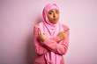© Krakenimages.com - Young African American afro woman wearing muslim hijab over isolated pink background Pointing to both sides with fingers, different direction disagree