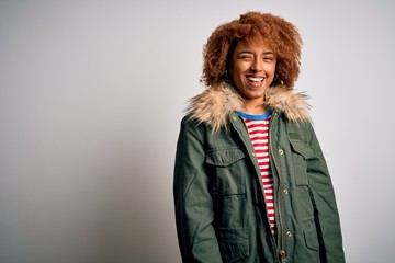 Wall Mural - Young beautiful African American woman with curly hair wearing green casual winter coat winking looking at the camera with sexy expression, cheerful and happy face.