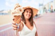 © Krakenimages.com - Young beautiful woman eating ice cream cone by the beach on a sunny day of summer on holidays