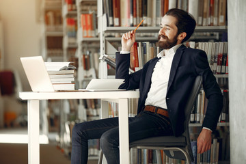 Wall Mural - Man in a library. Guy in a black suit. Student with a books.