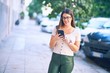 © Krakenimages.com - Young beautiful woman smiling happy and confident. Standing with smile on face using smartphone at the city