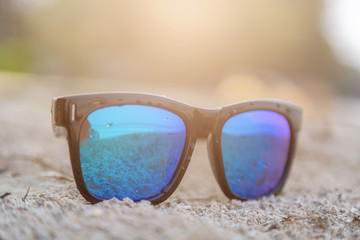 Blue sunglasses on white sand