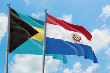 Paraguay and Bahamas flags waving in the wind against white cloudy blue sky together. Diplomacy concept, international relations.