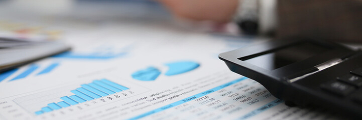 Black calculator and financial statistics on clipboard pad at office table closeup. Internal Revenue Service inspector sum check irs investigation earnings savings loan and credit concept