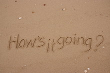 Inscription On The Sand, Handwriting  Words "How's It Going?" On Sand Of Beach.