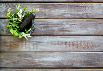 Wall Mural - Herbs in ceramic mortar with pestle on dark wooden backgroud top-down copy space