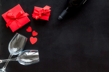 Valentines Day concept with wine, glasses, red present box on black background top-down copy space