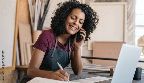 Fotografía Smiling entrepreneur talking on the phone in her framing studio