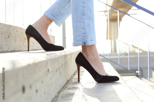 Fotografía Profile of woman legs wearing high heels walking down stairs