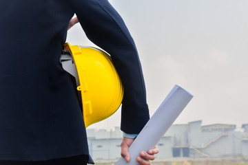 Engineering Construction holding yellow helmet blueprint at Construction background