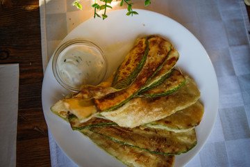 Baked sweet peppers in batter and fried zucchini in breadcrumbs on a plate. Traditional Bulgarian cuisine in the tourist cafe