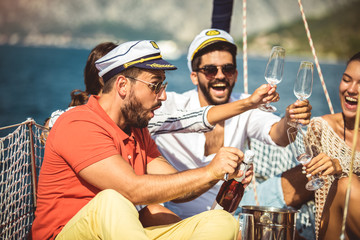 Wall Mural - Smiling friends with glasses of champagne on yacht. Vacation, travel, sea, friendship and people concept