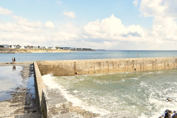 Wall Mural - Audierne ville du Finistère en Bretagne sa baie son phare sa jetée le pont et les vagues qui se jettent sur les rochers en projetant de l'écume à marée haute